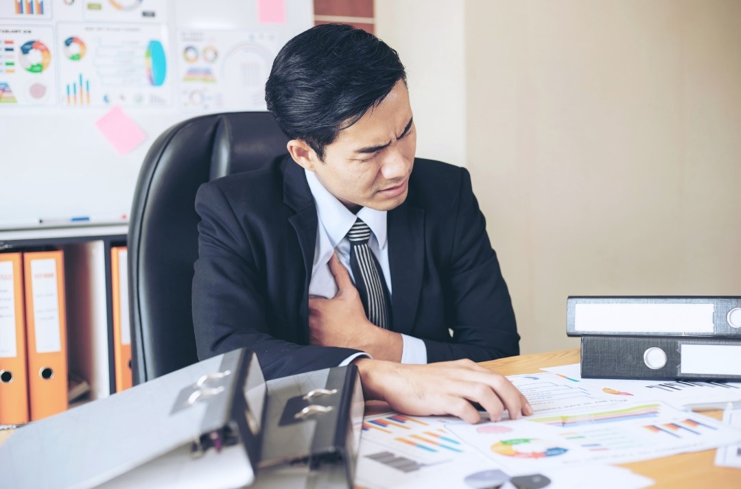 a man having chest pain in the midst of work